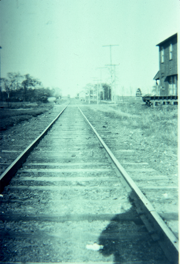 View of tracks looking east at North Maple Avenue. A corner of the old soap Factory appears in the upper right corner.